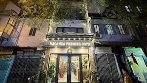 The exterior of Vacanza Premier Hotel with a sign above the entrance, surrounded by trees and other buildings.