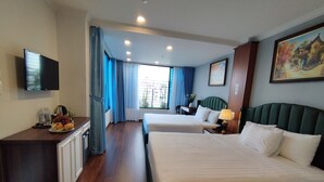 A hotel room with two beds, a desk with a computer, a TV, and a window with curtains.