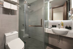 Een moderne badkamer met een douchecabine van glas, een wit toilet en een marmeren wastafel met toiletartikelen.