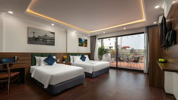 A hotel room with two beds, a desk, a TV, and a balcony with a view.