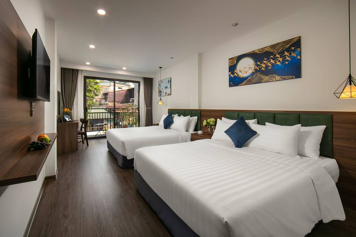 A hotel room with two beds, a TV, a balcony with a view, and artwork on the walls.