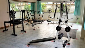 Une salle de sport équipée de divers appareils d’exercice, notamment des tapis de course, des appareils de musculation et des poids libres.