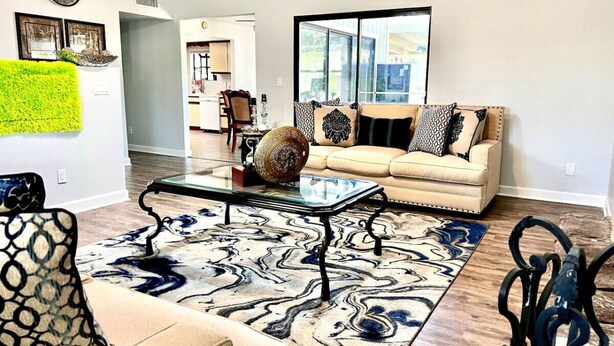 Un salon avec un canapé, une table basse, un tapis à motifs et une vue sur l’extérieur.