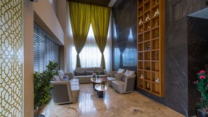 A modern living room with a sectional sofa, a coffee table, and a decorative shelf. - Hotel Park Elite (Gannavaram)