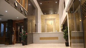 A hotel lobby with a reception desk, a large mirror, and a potted plant. - Hotel Park Elite (Gannavaram)