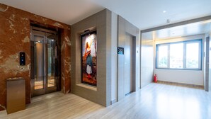 A modern lobby with marble walls, an elevator, and a large window. - Hotel Park Elite (Gannavaram)