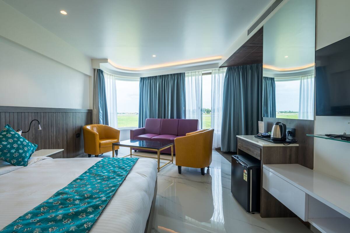 Een hotelkamer met een bed, een bureau, een stoel, een bank en uitzicht op de omgeving.