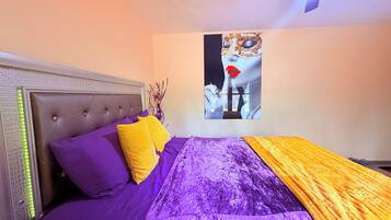 A bed with a tufted headboard, purple bedding, and a yellow throw.