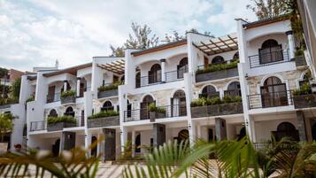 A multi-story hotel with white exterior walls, arched windows, and balconies with greenery.