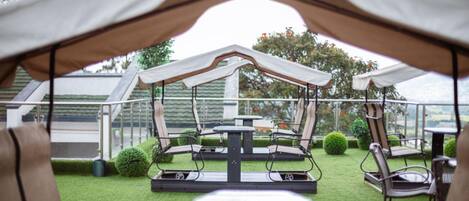 An outdoor patio area with a covered seating arrangement, tables, and chairs.