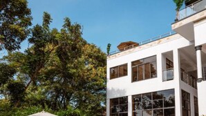 Un edificio moderno con piscina, sillas de descanso y sombrillas.