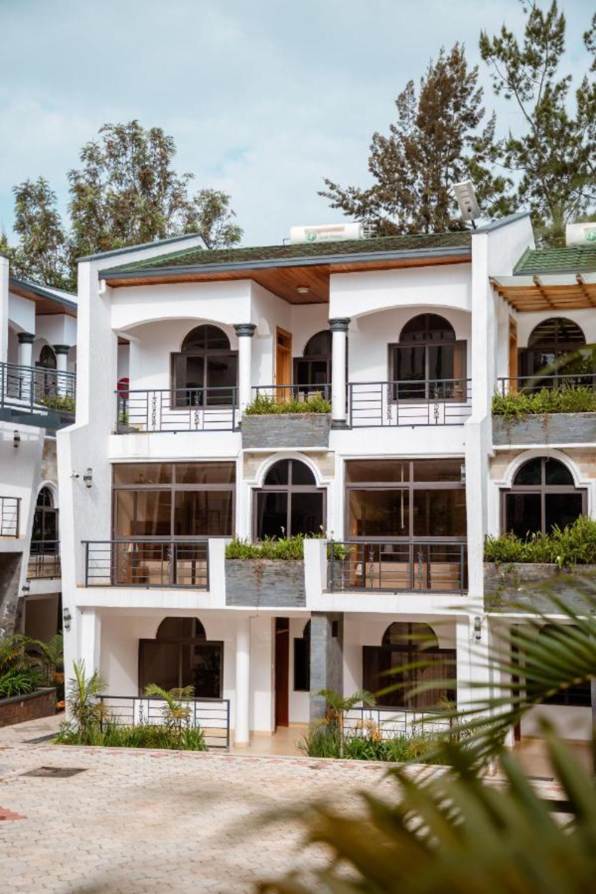 A multi-story building with balconies, large windows, and a courtyard with plants.