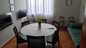 Ein Essbereich mit rundem Tisch, Stühlen, einem Fernseher und einer Couch.