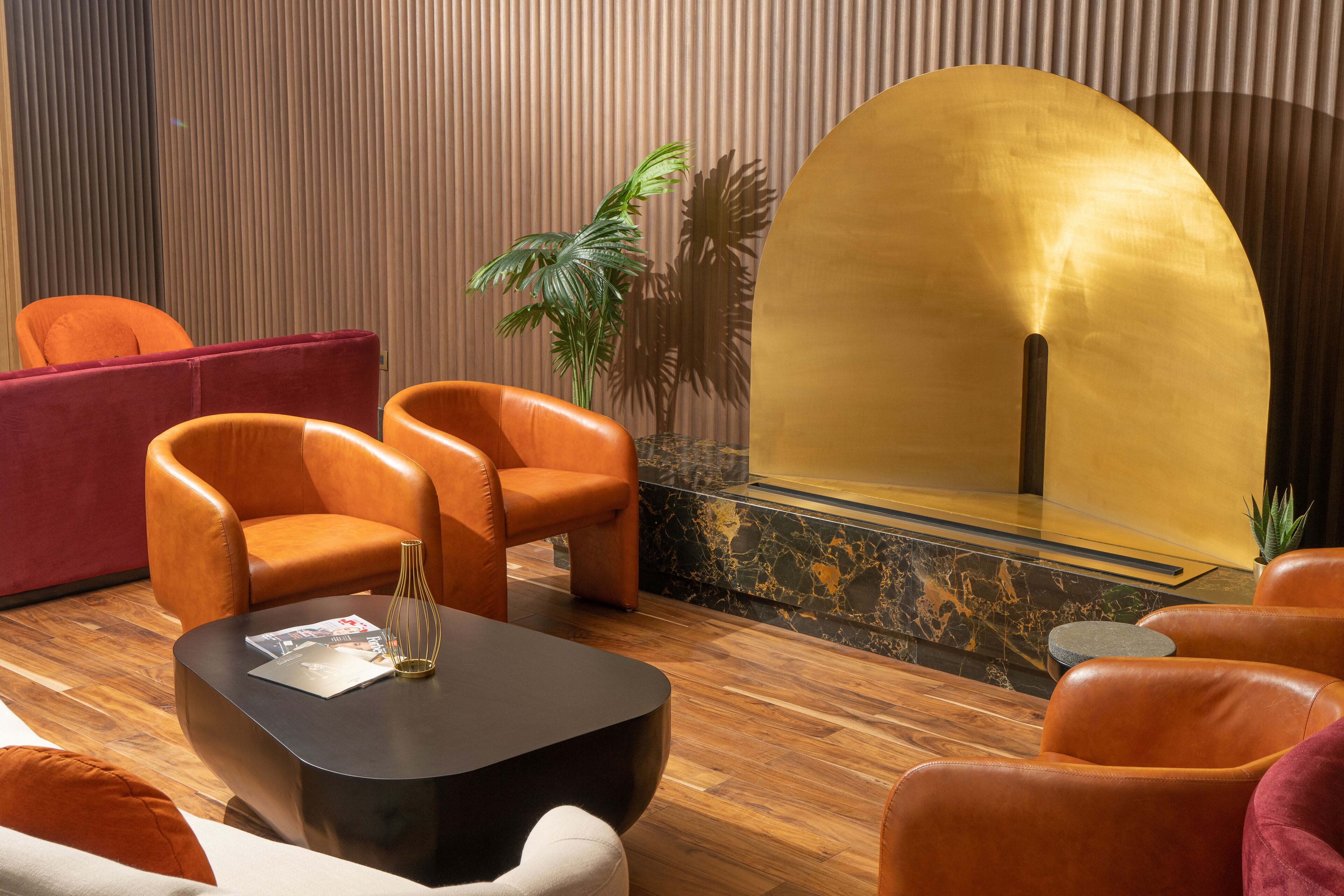 A modern lobby with leather armchairs, a black coffee table, and a golden reception desk.