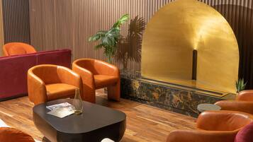 A modern lobby with leather armchairs, a black coffee table, and a golden reception desk.