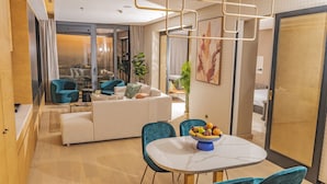 Ein modernes Hotelzimmer mit Essbereich, einer Sofagarnitur und einem großen Fenster.