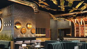 Ein modernes Restaurantambiente mit Backsteinwand, runden Wandleuchten und einer Bar.