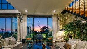 Amplia sala de estar con un sofá grande, una mesa de centro y vistas a la puesta de sol a través de amplias ventanas.
