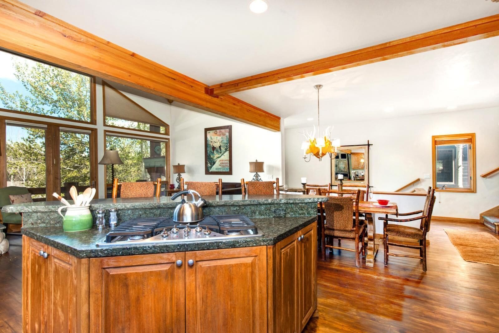 Una cocina amplia con una isla grande, muebles de madera y un comedor con candelabro.