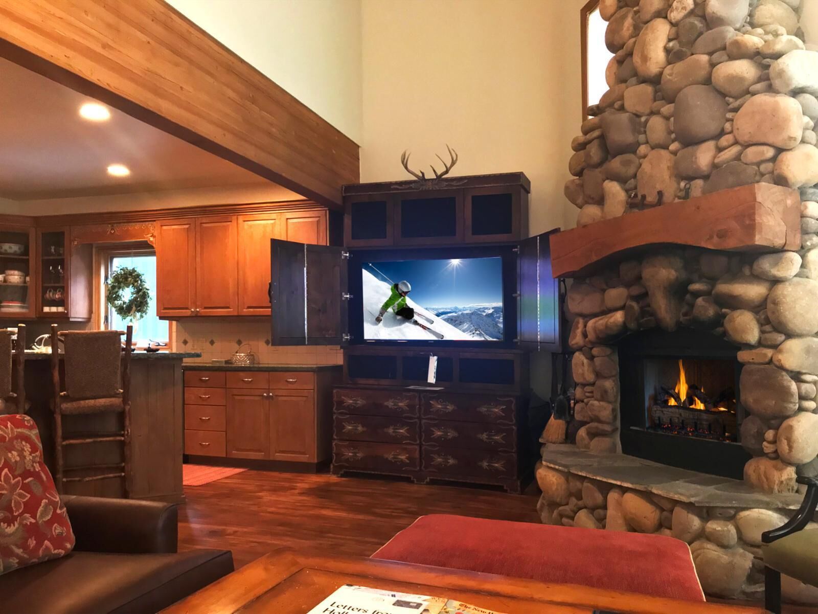 A living room with a stone fireplace, wooden cabinets, a television, and a cozy seating area.