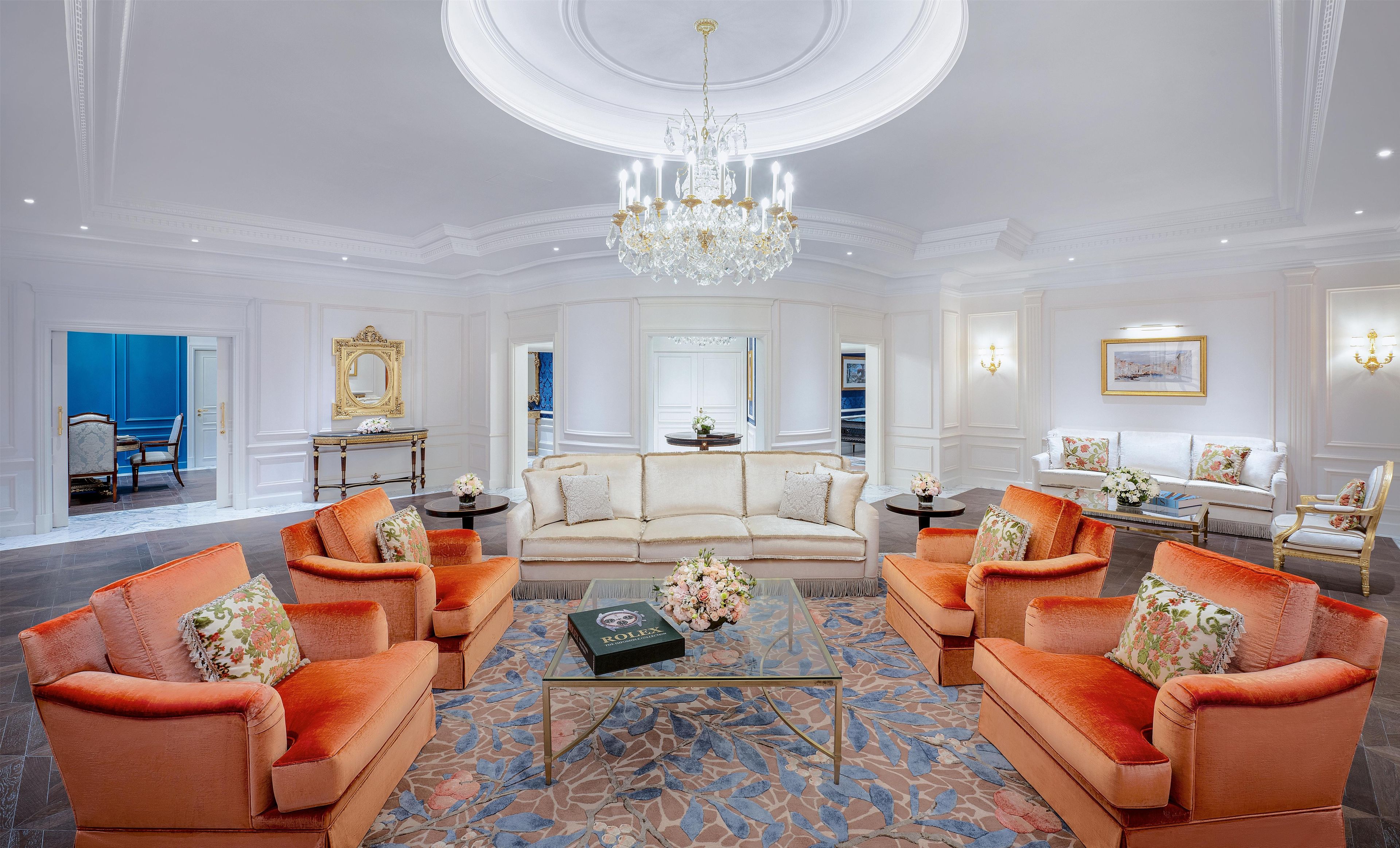 Un salón lujoso con candelabro, sofás y una mesa de centro.