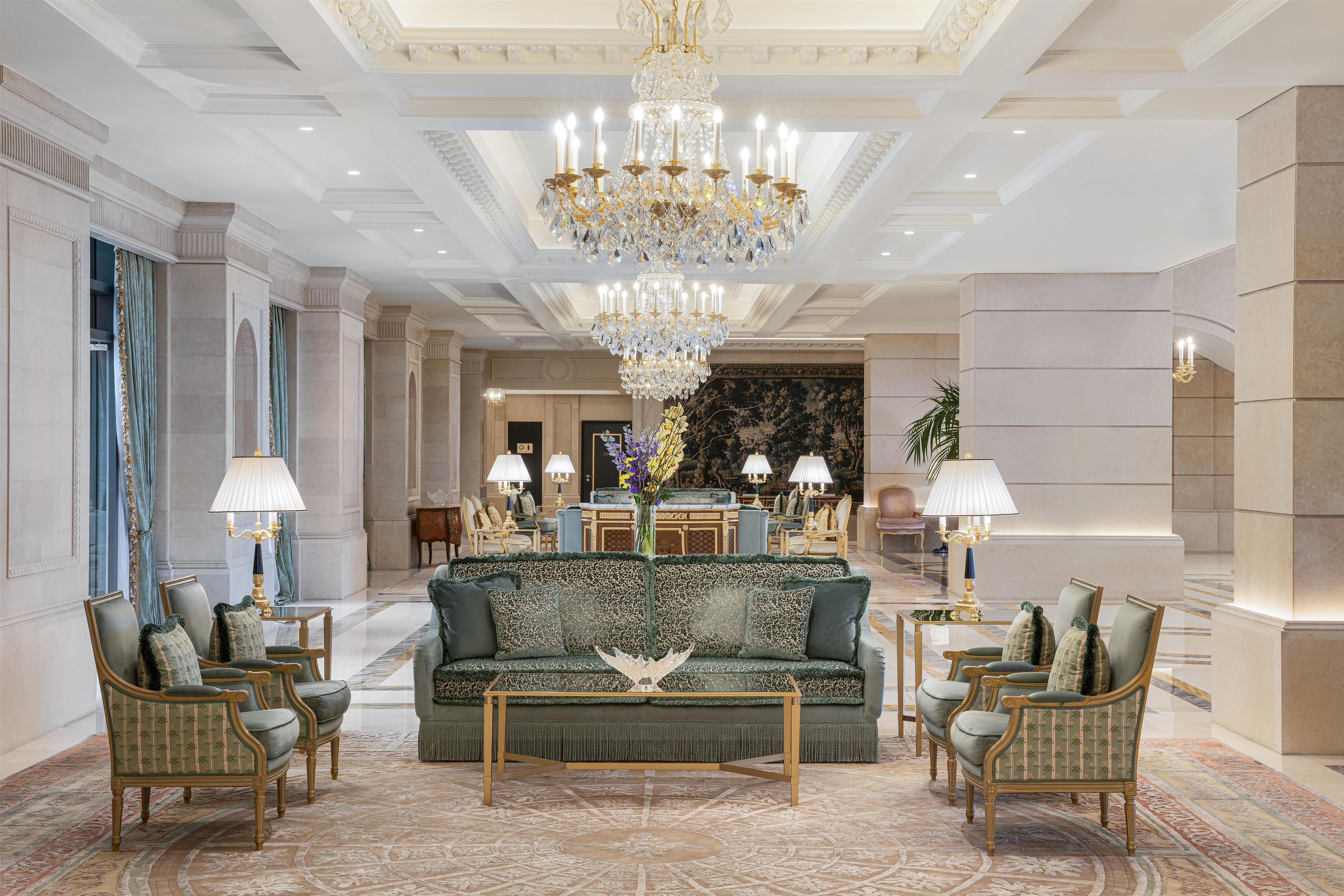 A luxurious lobby with a grand chandelier, plush seating, and elegant decor.