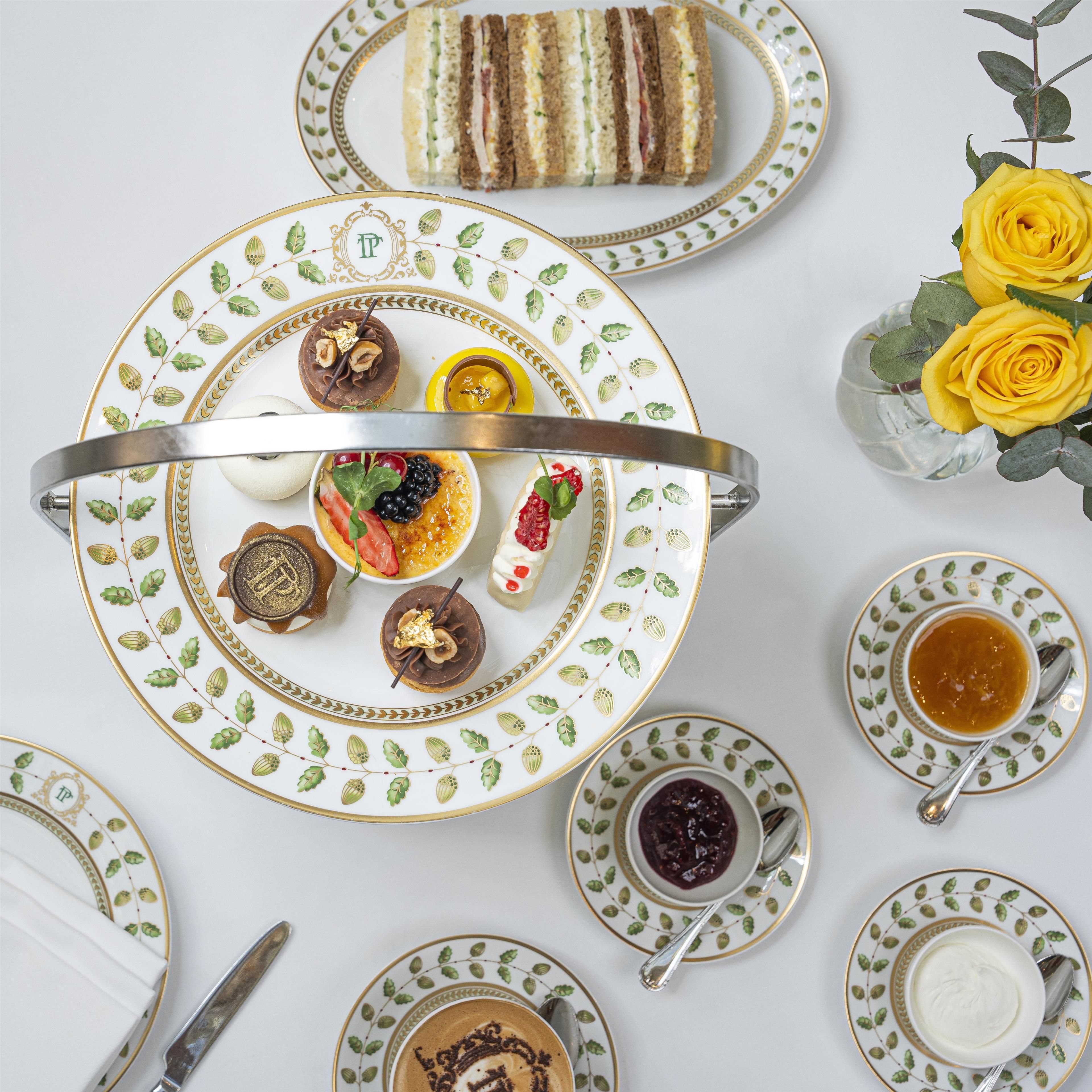 Una mesa dispuesta con diversos alimentos, como sándwiches, pasteles y bebidas, presentados en vajilla decorada.