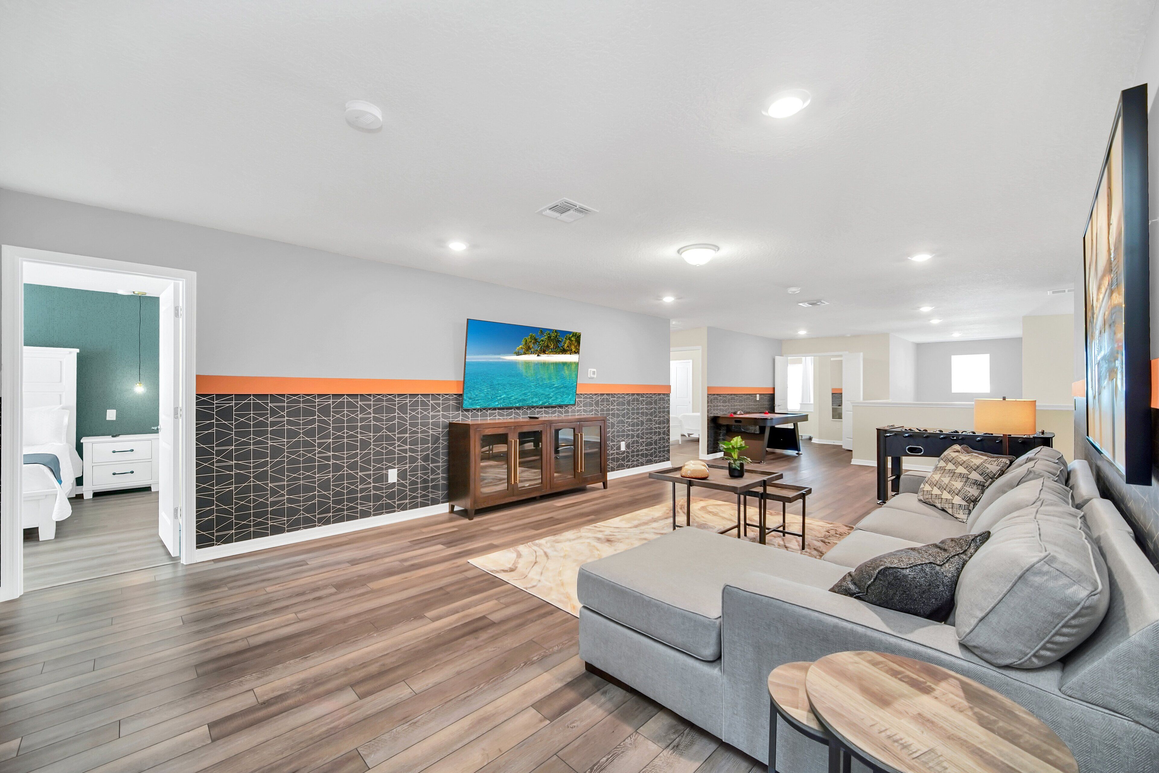A spacious living area with a grey sofa, wooden coffee table, and a kitchen in the background.