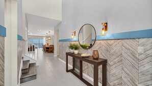 A modern hallway with a herringbone-patterned wall, a console table with decorative items, and a large mirror. - Luxury 8BR Villa Near Disney | Private Pool & Spa | Windsor Island Resort (Davenport)
