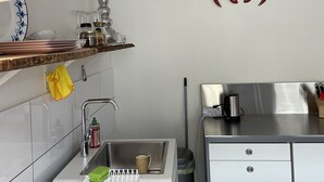 Una cocina moderna con un lavamanos, una toalla amarilla, un refrigerador de acero inoxidable y un adorno de pared con forma de cangrejo rojo.