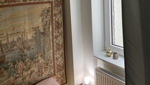 A bedroom with a large tapestry on the wall, a window with a view of the outside, and a radiator near the window. - Good times in St. Goar (Sankt Goar)