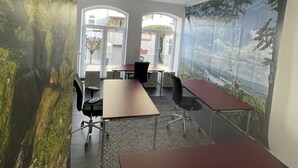 A conference room with a stone wall mural, large windows, and a view of a cityscape. - Good times in St. Goar (Sankt Goar)
