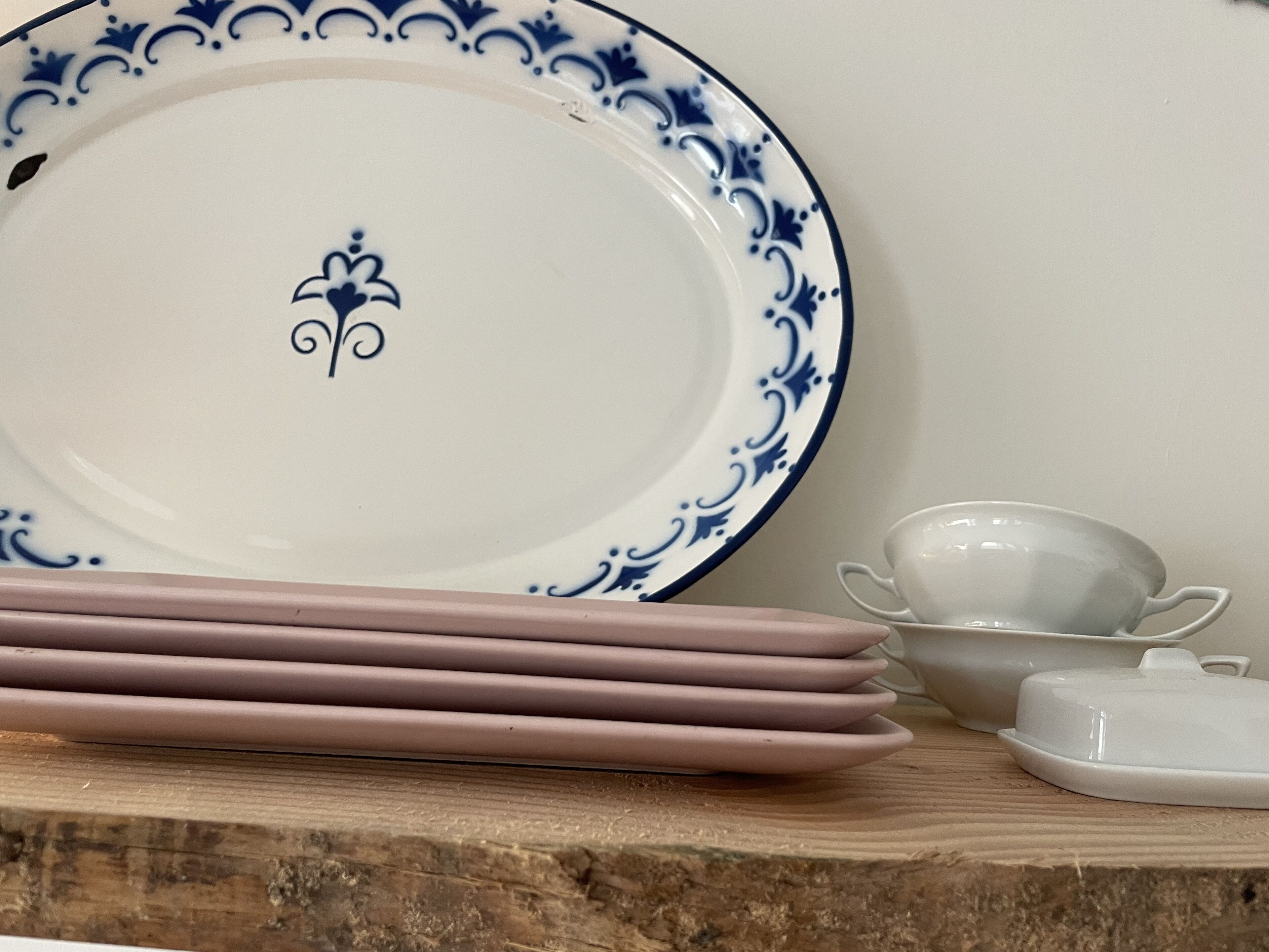 Un mucchio di piatti rosa e una tazza bianca su un tavolo di legno.