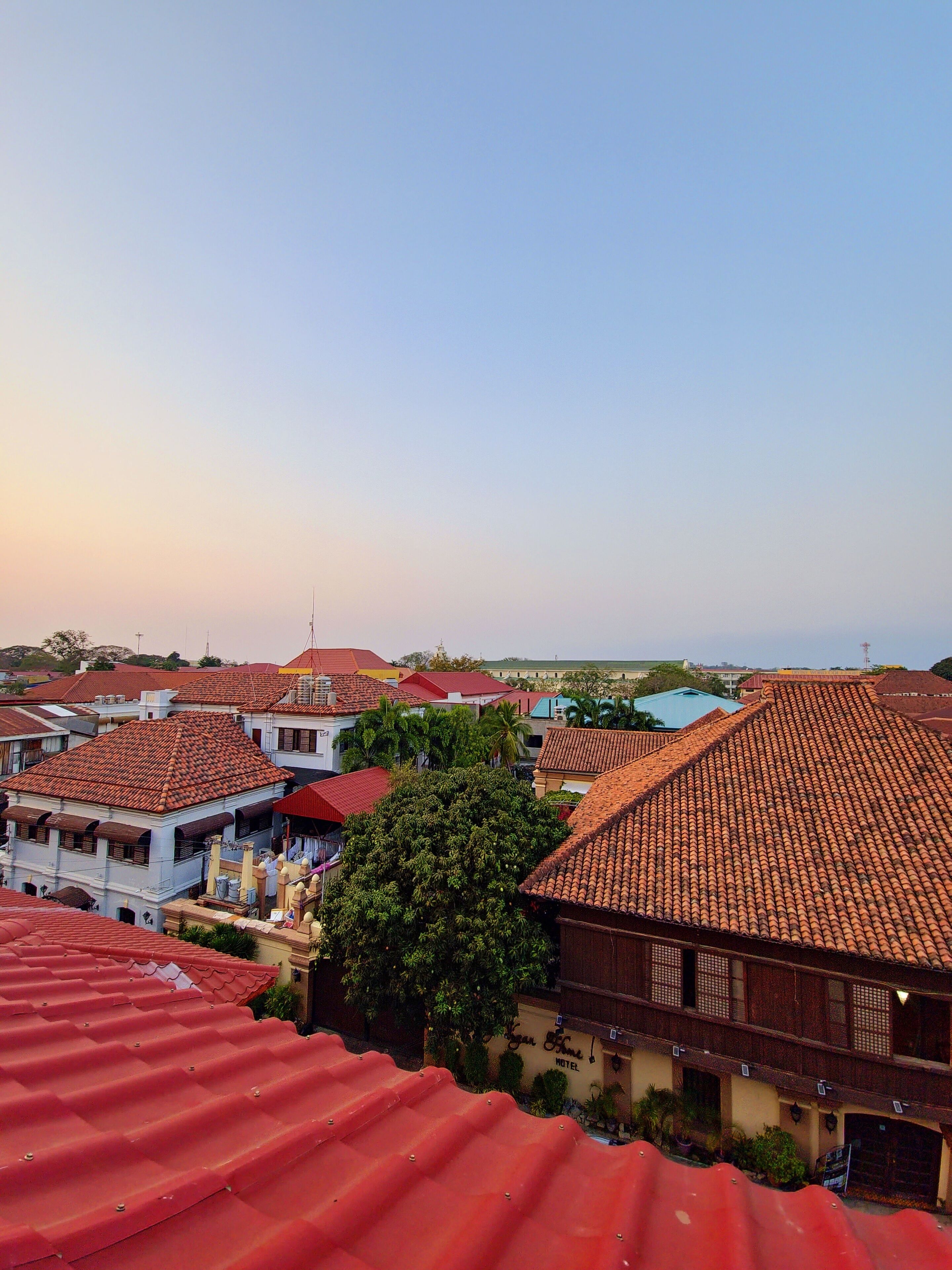 A view of a residential area with red-tiled roofs and a hotel with a sign reading "Yuan Fine Hotel".
