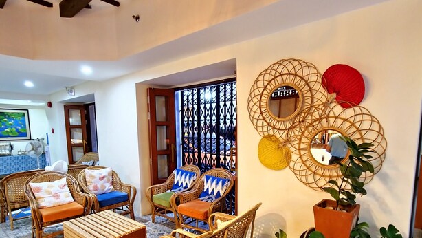 A cozy living room with wicker furniture, a patterned rug, and a decorative wall piece. - Hotel Mercante (Vigan)