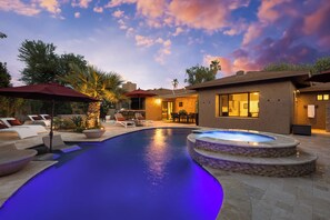 A swimming pool with a hot tub, lounge chairs, and a patio area with outdoor seating.