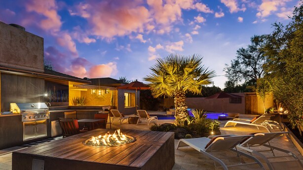 Un área de cocina al aire libre con una parrilla, mesa de comedor y sillones de descanso.
