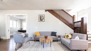 Ein Wohnzimmer mit grauem Sofa, einem runden Couchtisch und einem gemusterten Teppich.