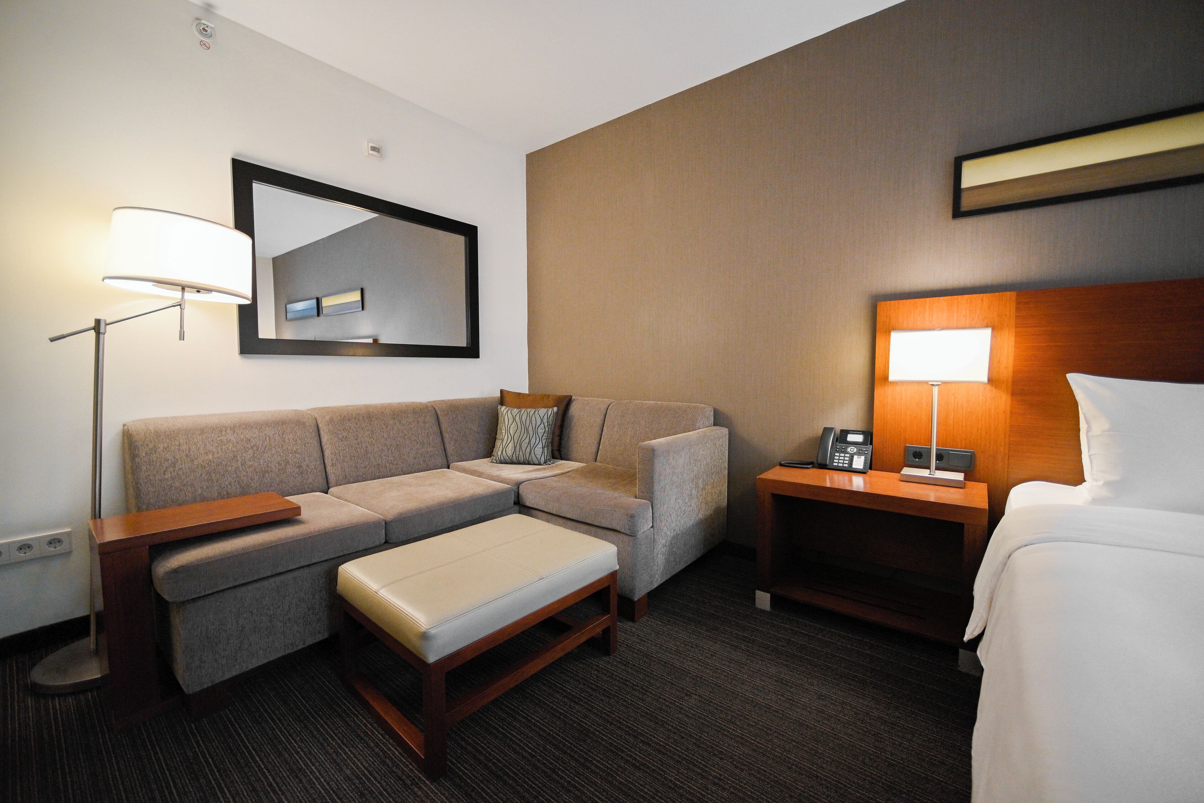 Una habitación de hotel con sofá, una mesita, una mesita de noche con lámpara y una cama.