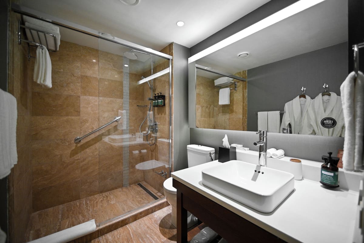 A modern bathroom with a glass-enclosed shower, a white sink, and a large mirror.