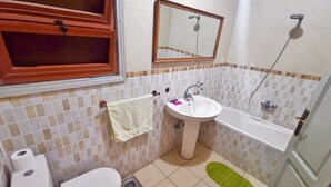 Casa de banho com sanita, lavatório e banheira.