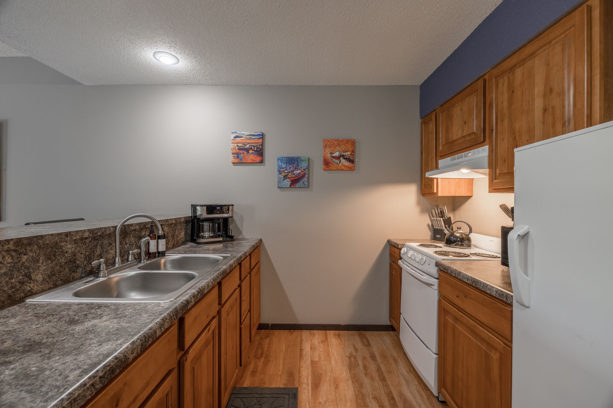 A kitchen with granite countertops, wooden cabinets, a white refrigerator, and a stove.