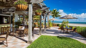 A beachside patio with outdoor seating, a sign for 'Abbey Road Snack Shack', and a view of the ocean.