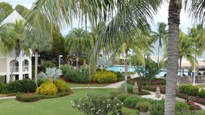 Ett semesterhotell med en pool, palmer och en vit byggnad med valv.