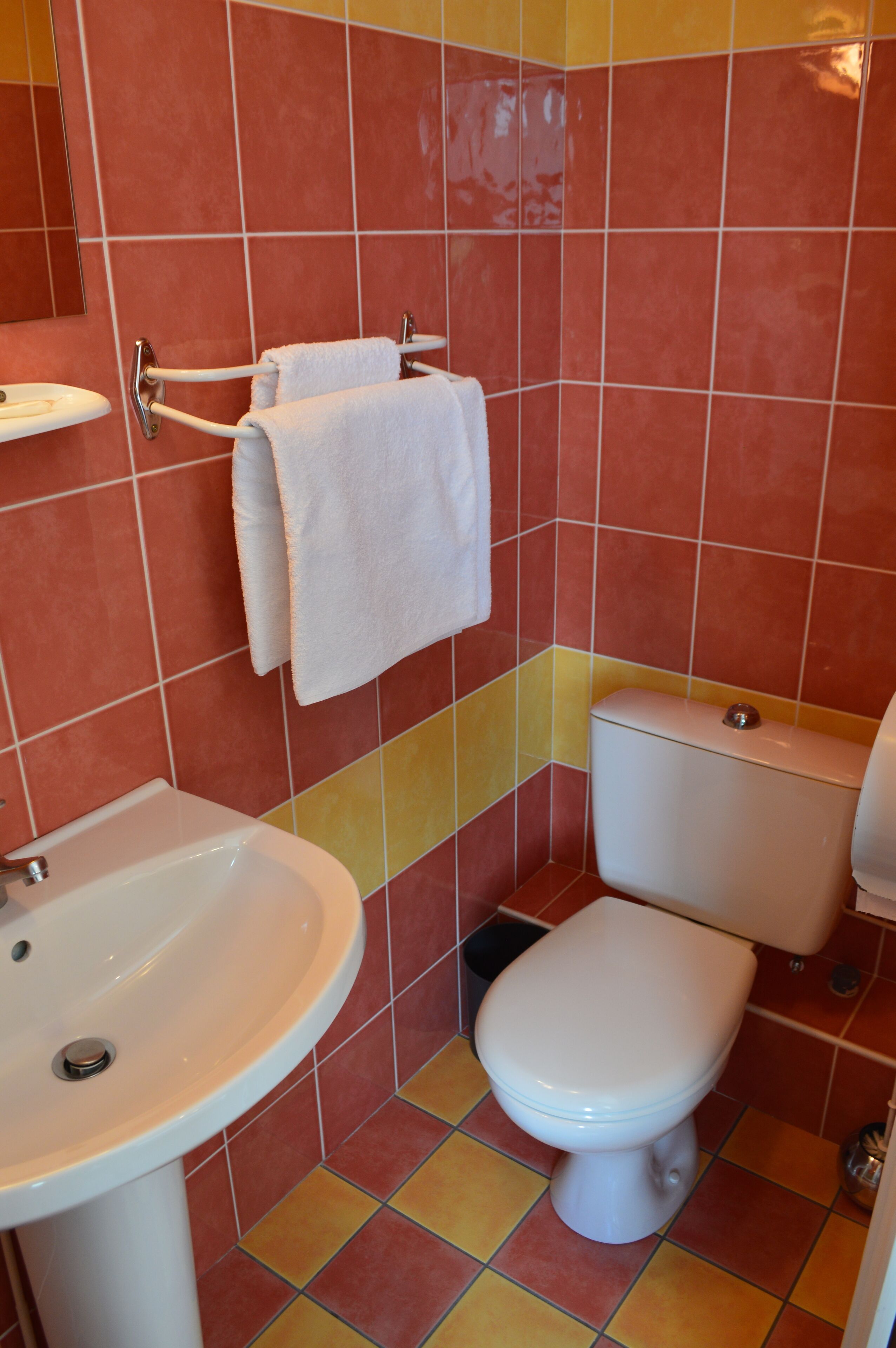 A bathroom with a sink, toilet, and towel rack.