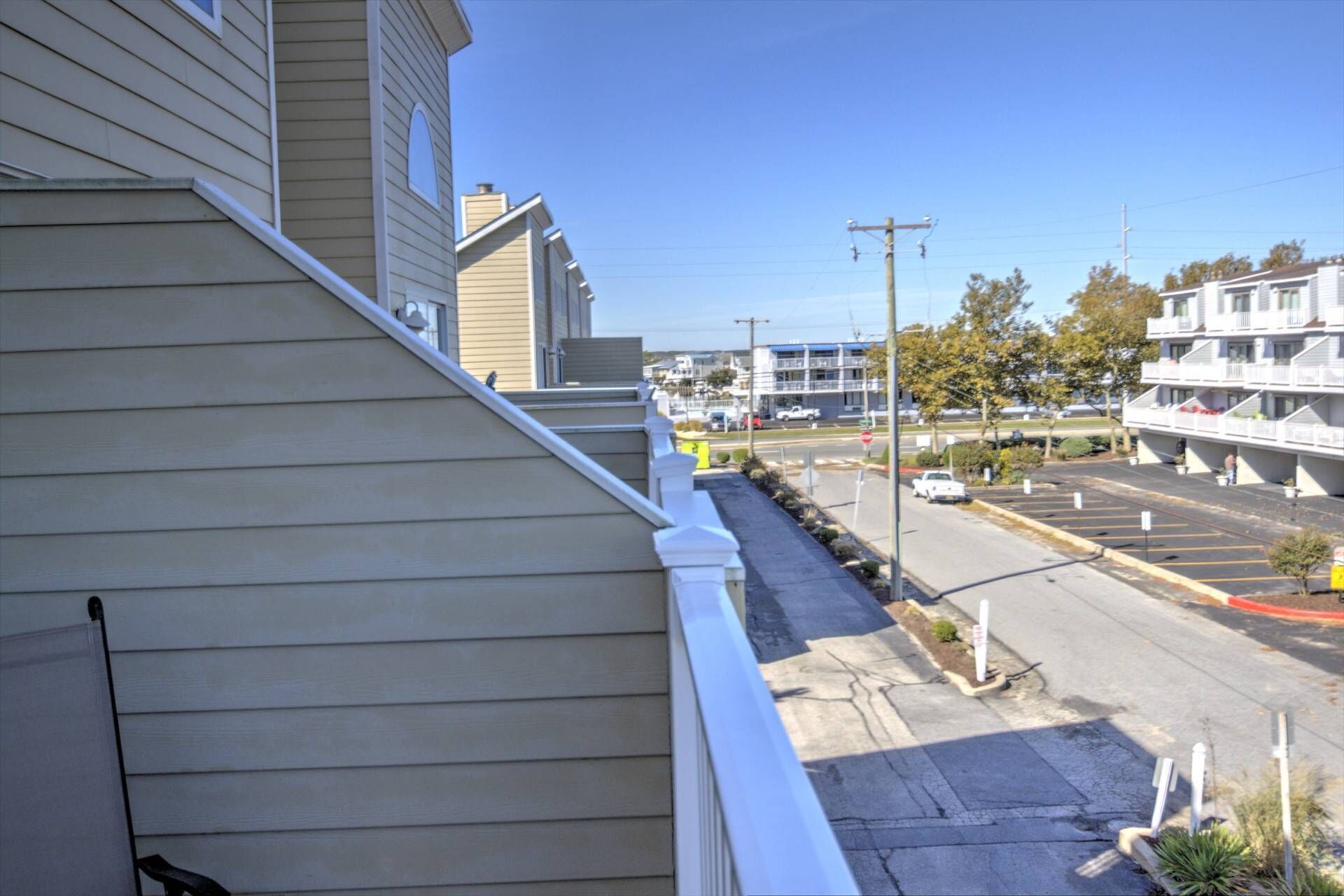 A residential street with houses, a parking lot, and a clear sky.