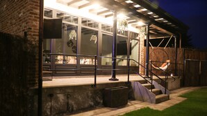 Un espace patio comprenant un banc en béton, un fauteuil suspendu et un escalier menant à un niveau supérieur.