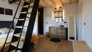 Une chambre à coucher avec un escalier en bois, un lit, une commode et un miroir.