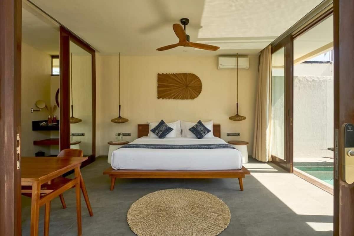 Ein Schlafzimmer mit einem Bett, Nachttischen, einem Deckenventilator und Blick auf einen Pool.