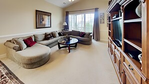 A living room with a sectional sofa, a round coffee table, and a TV stand.